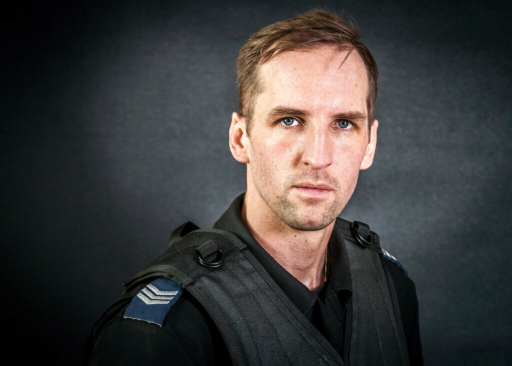 portret mundurowy, policja, policjant, mundur służbowy czarny bez czapki, kamizelka taktyczna